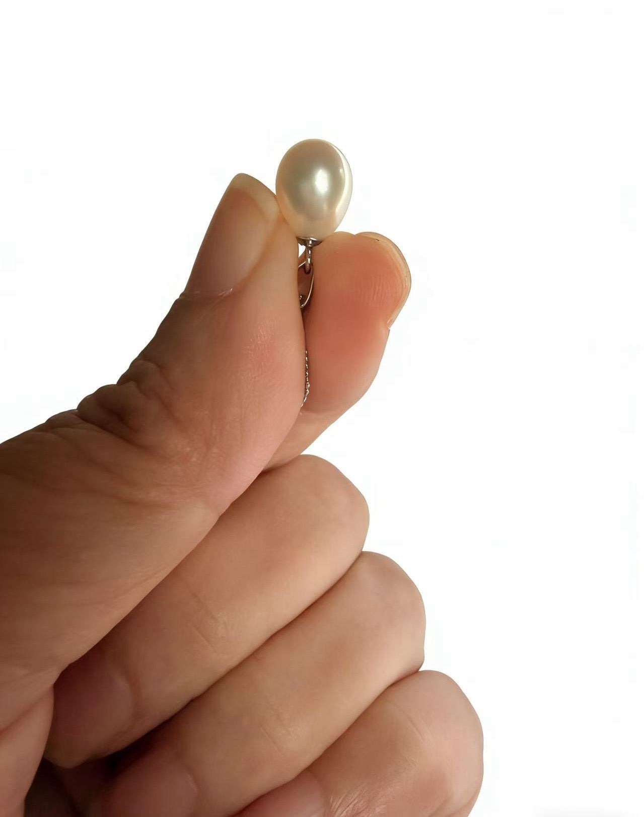Hand holding a lustrous cream-white baroque freshwater pearl pendant on a delicate 925 sterling silver chain.