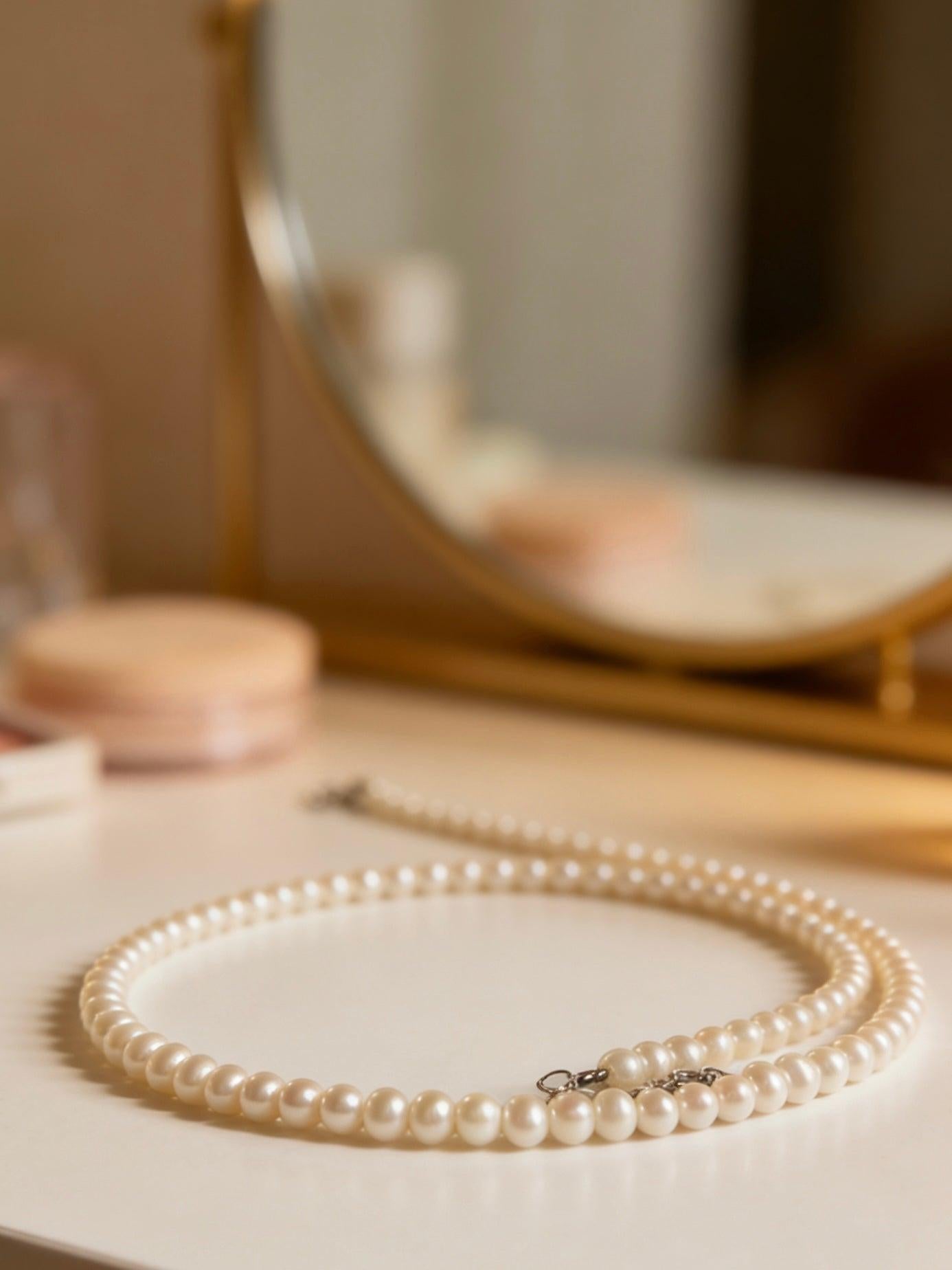 Minimalist 3-4mm round freshwater pearl necklace with 925 sterling silver clasp on a silk background.