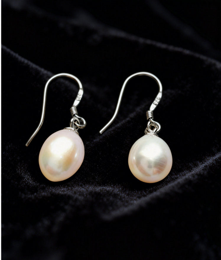Baroque freshwater pearl drop earrings with 7-8mm white pearls on 925 sterling silver hooks against black velvet.