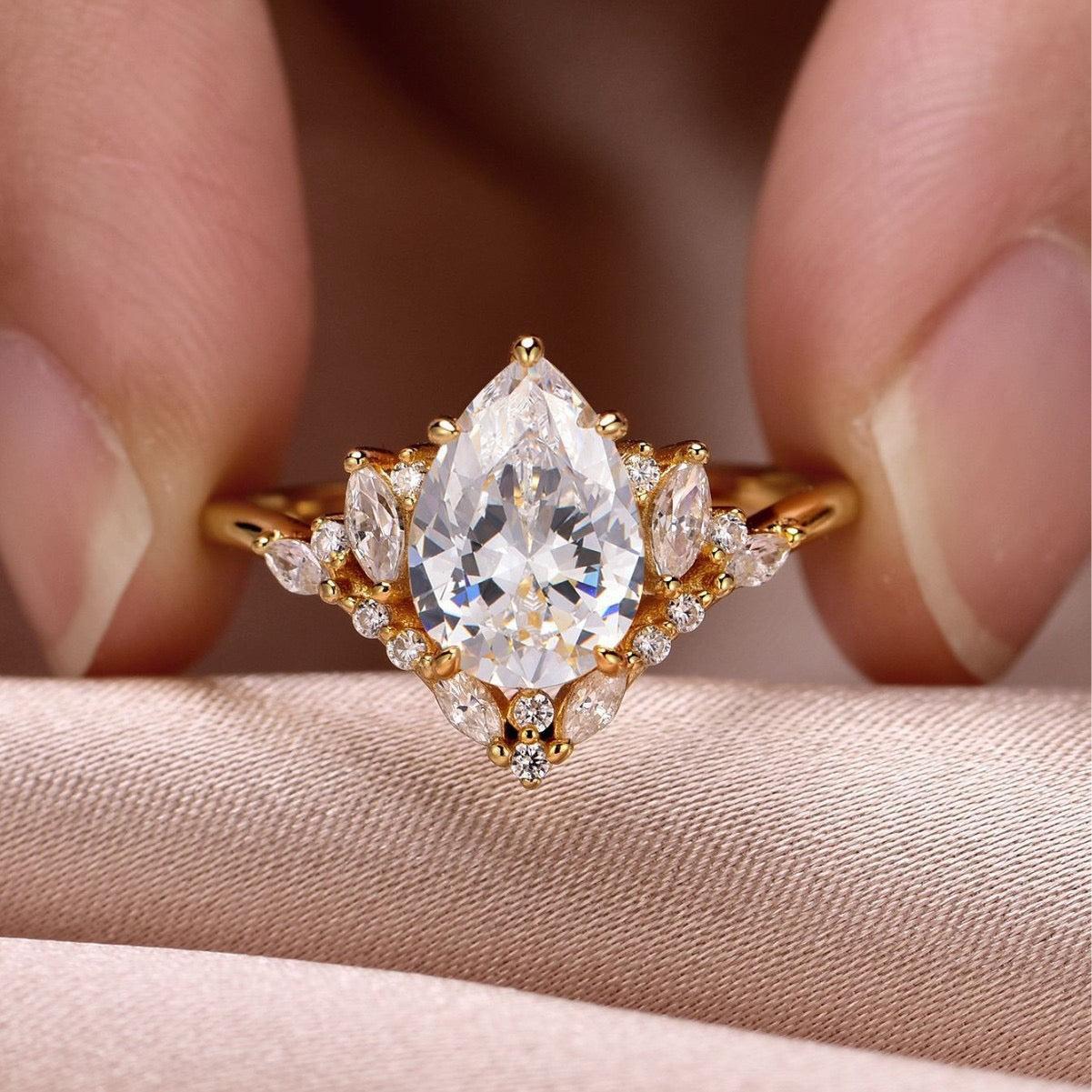 8x12mm pear-cut moissanite ring in gold with marquise and pavé halo accents.