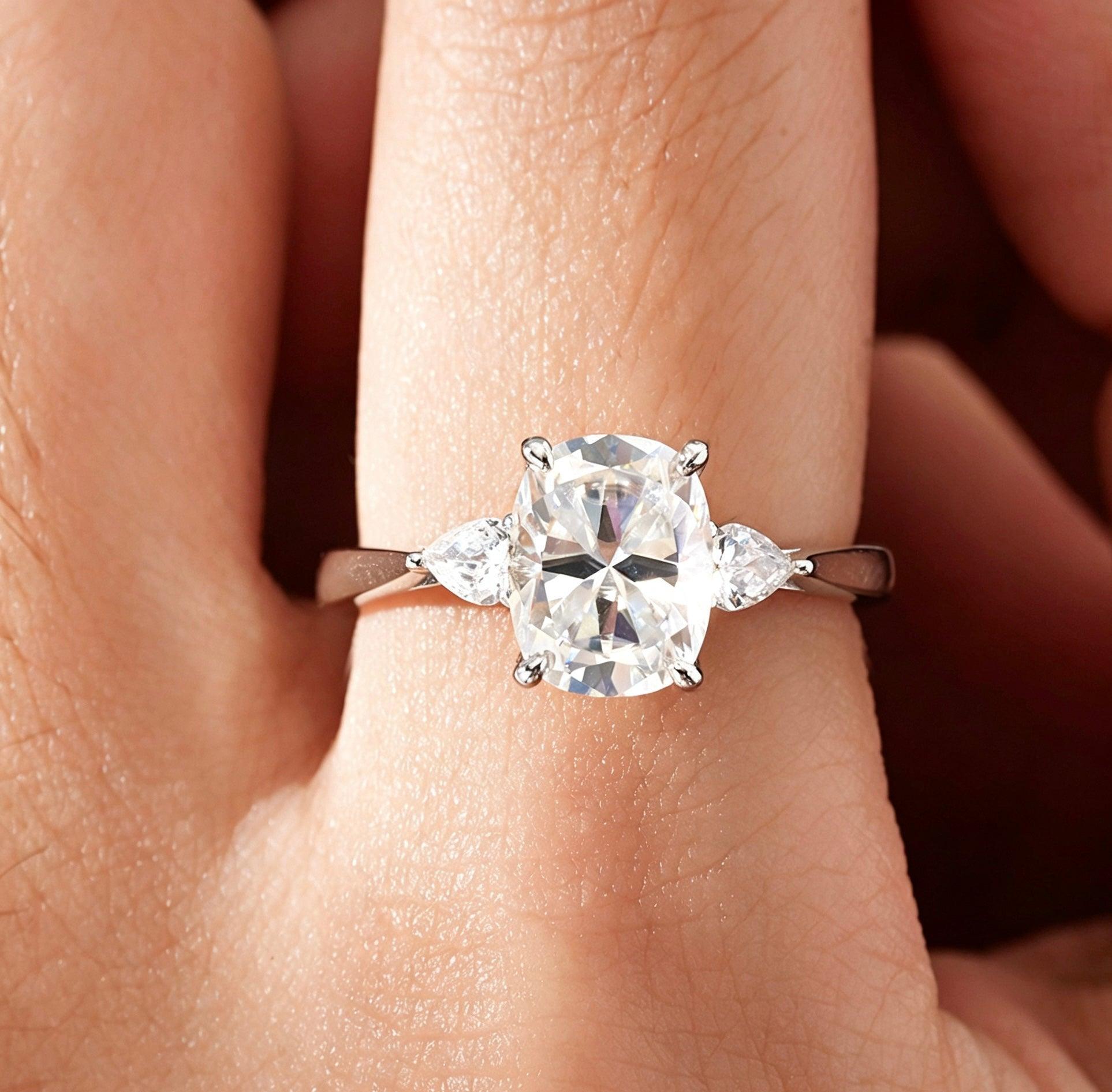 7x9mm cushion cut moissanite engagement ring with pear side stones in a vintage S925 silver three-stone setting.