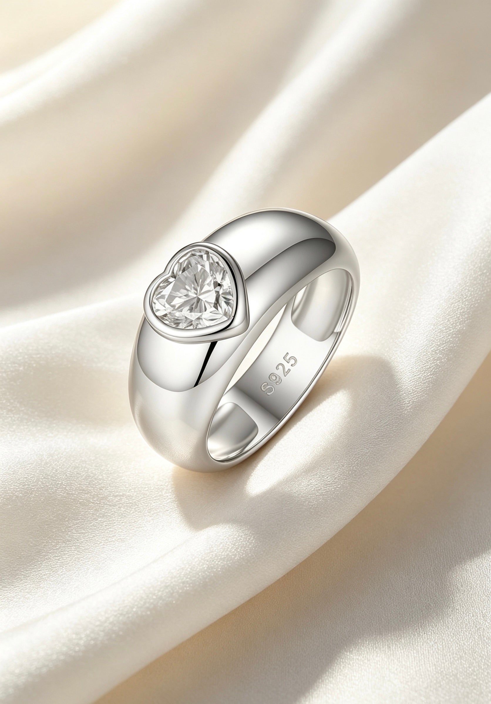1.2ct heart-cut moissanite ring in a polished S925 silver dome band with a modern bezel setting on white silk.