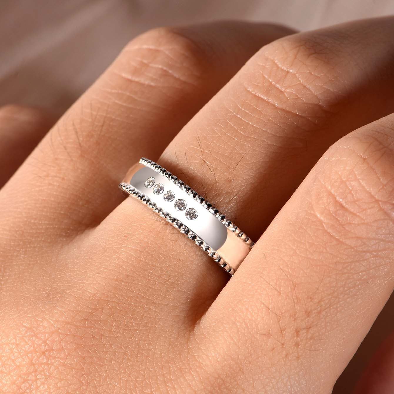 Wide silver men's wedding band with beaded edges and five sparkling D-color moissanite stones on a finger.