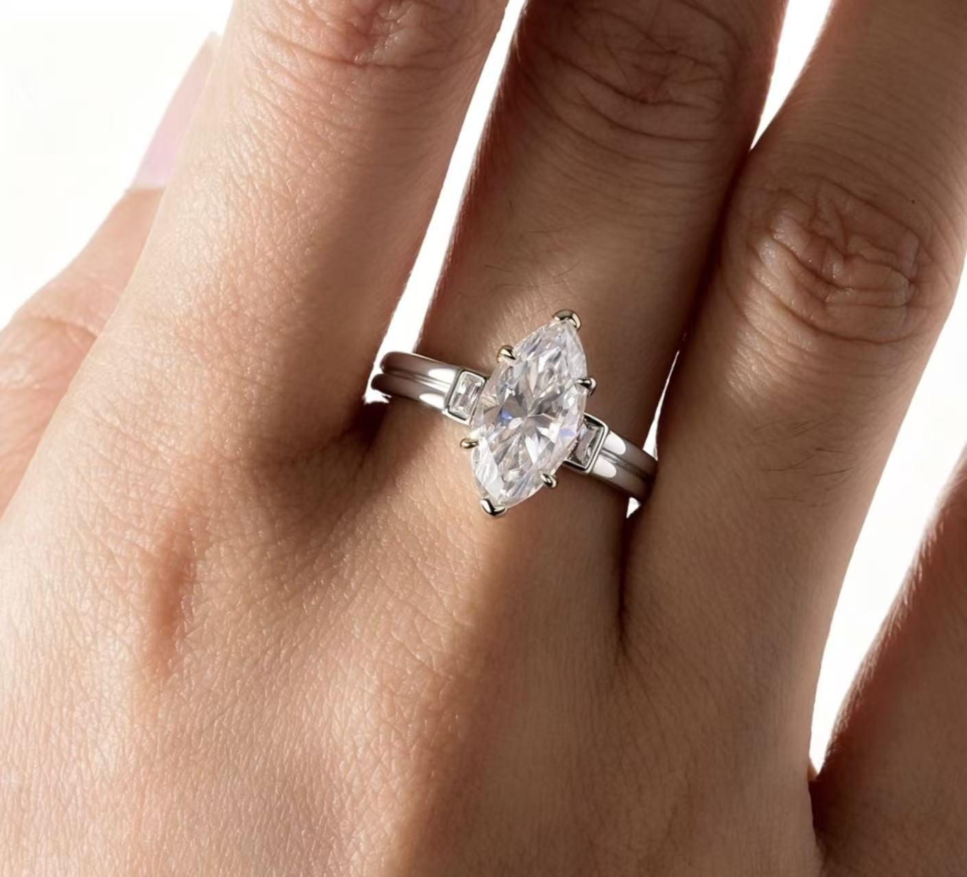 3.0ct marquise-cut moissanite trinity engagement ring in S925 sterling silver with baguette side stones on a finger.