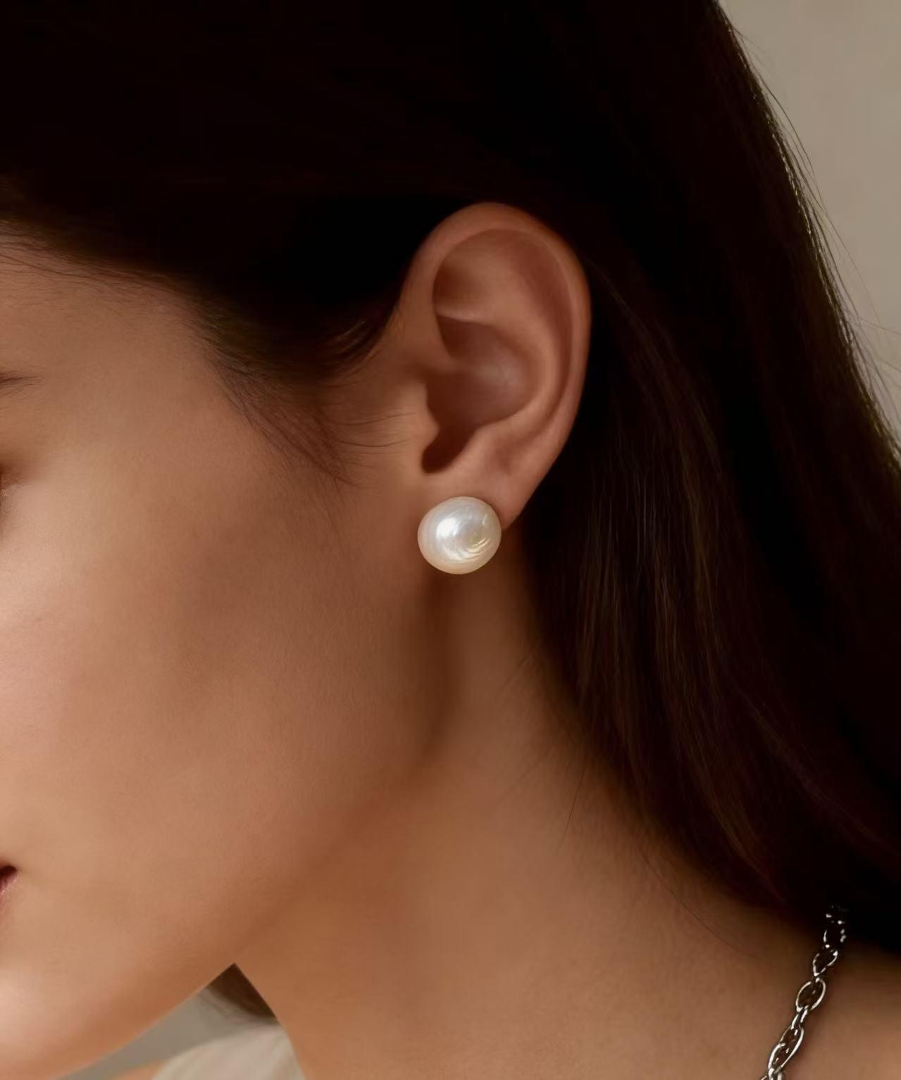 7mm natural white freshwater pearl stud earrings with sterling silver posts worn on a woman's ear.