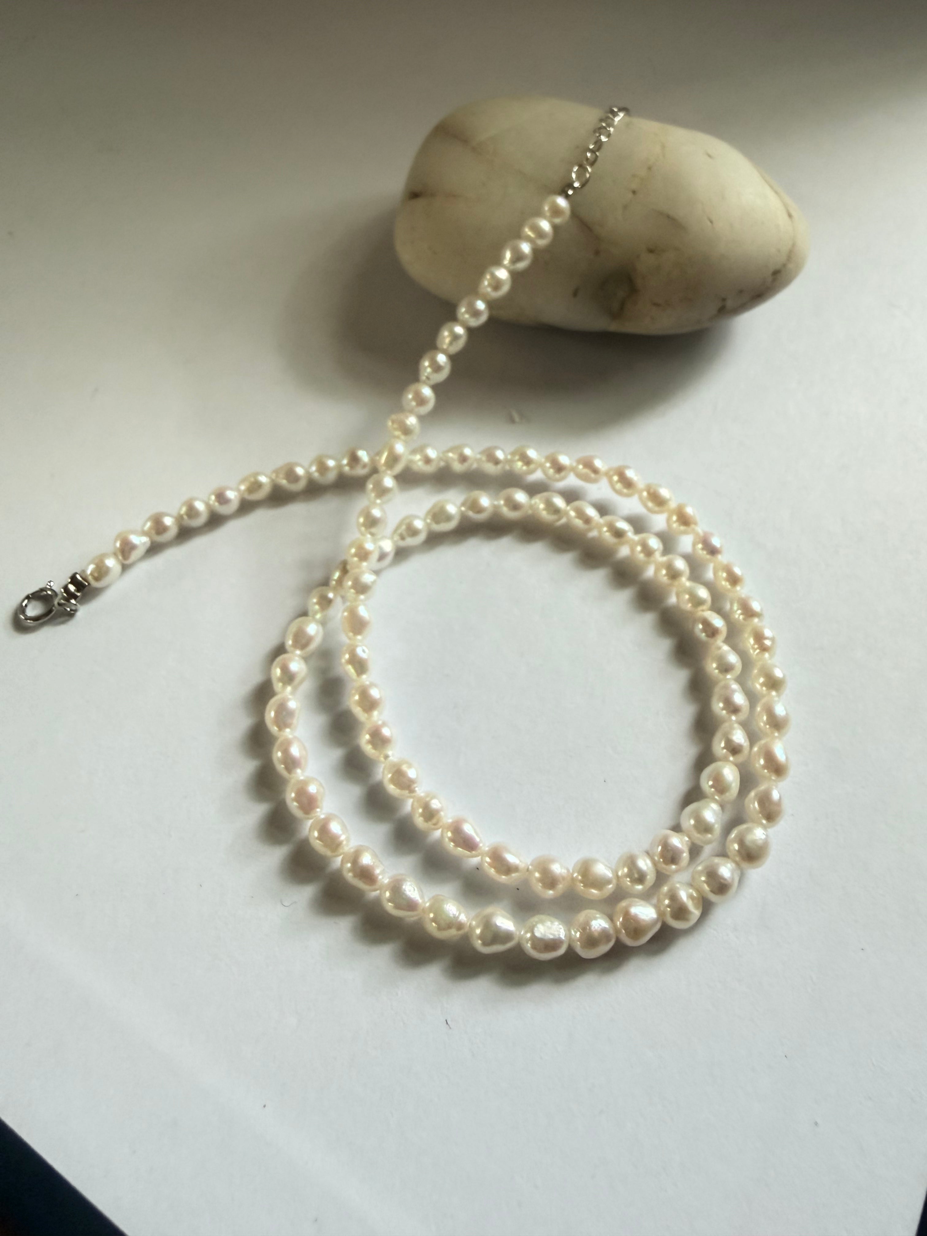 Minimalist 3–4mm baroque freshwater pearl seed necklace with 925 sterling silver clasp on a white surface.