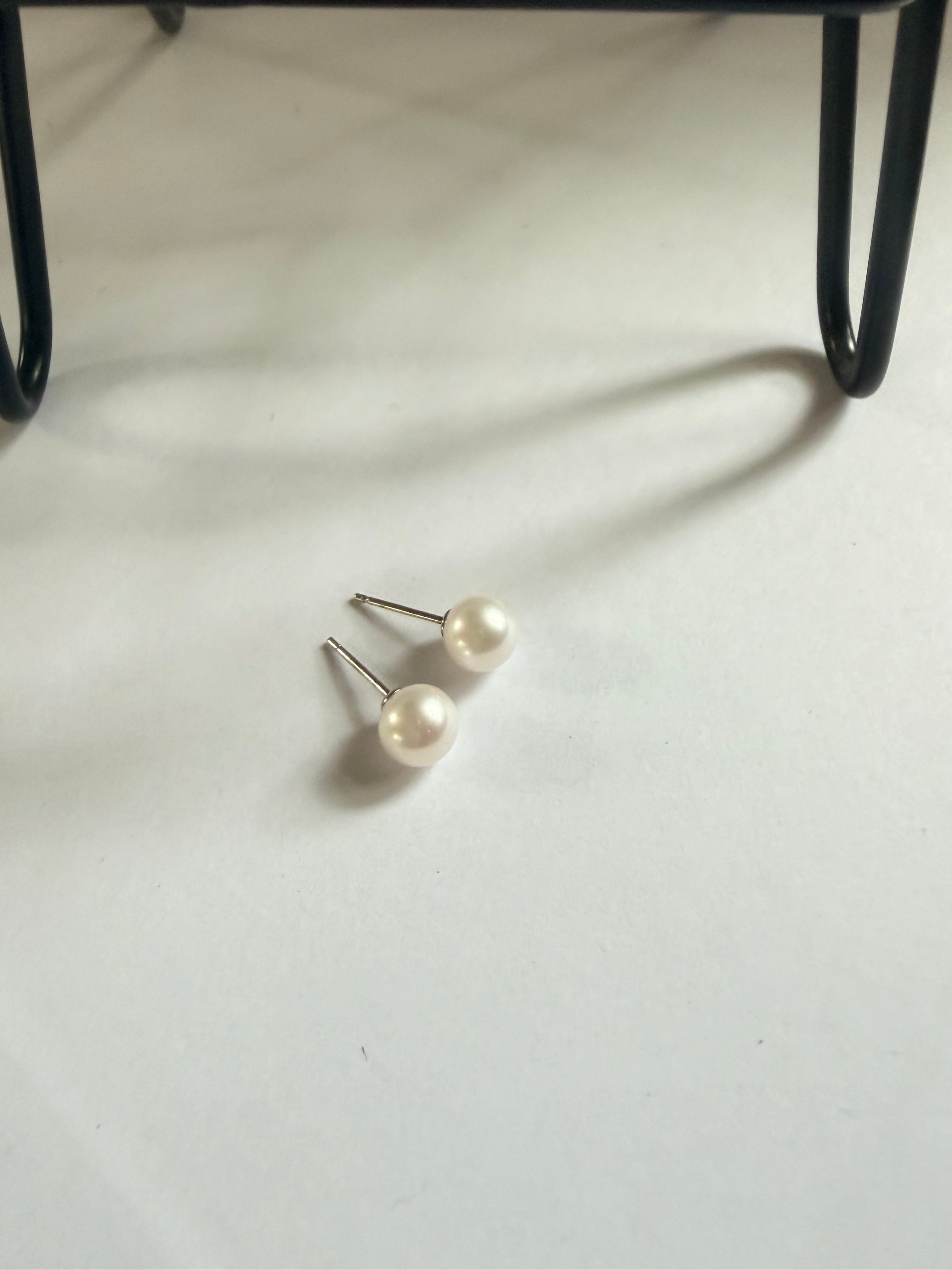 7mm white freshwater pearl stud earrings with sterling silver posts on a white surface.