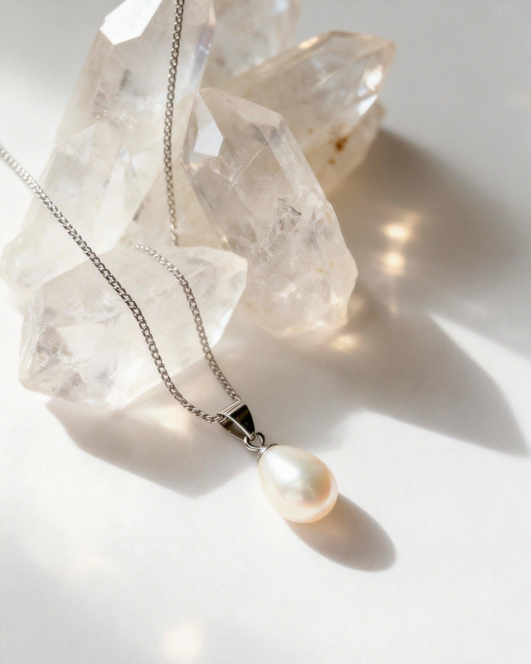 Baroque freshwater pearl pendant on a delicate 925 sterling silver chain, displayed against clear quartz crystals.