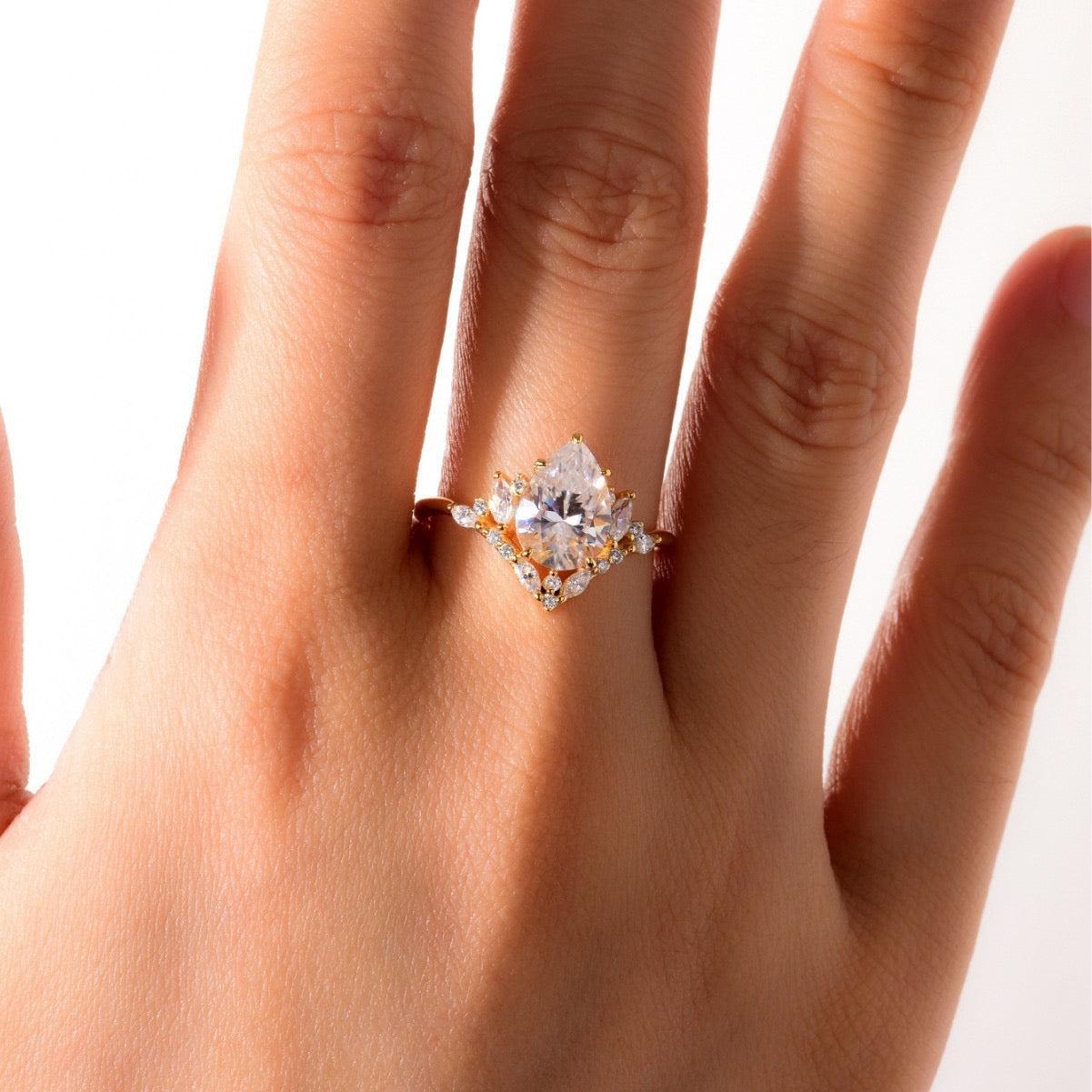 8x12mm pear-cut moissanite halo ring in gold-plated S925 silver with marquise and pavé accents on a finger.