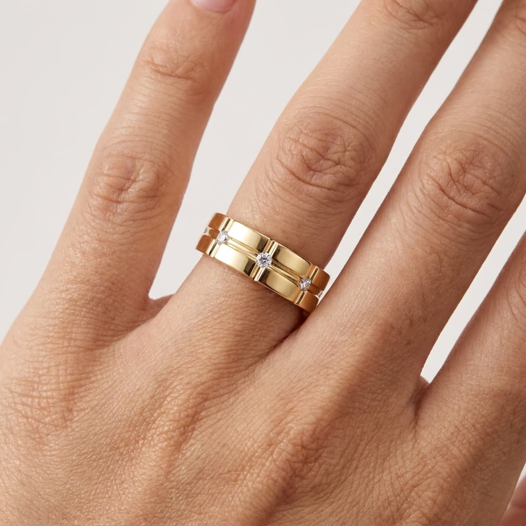 Wide gold-tone wedding band with a geometric grid pattern and seven flush-set moissanite stones worn on a finger.