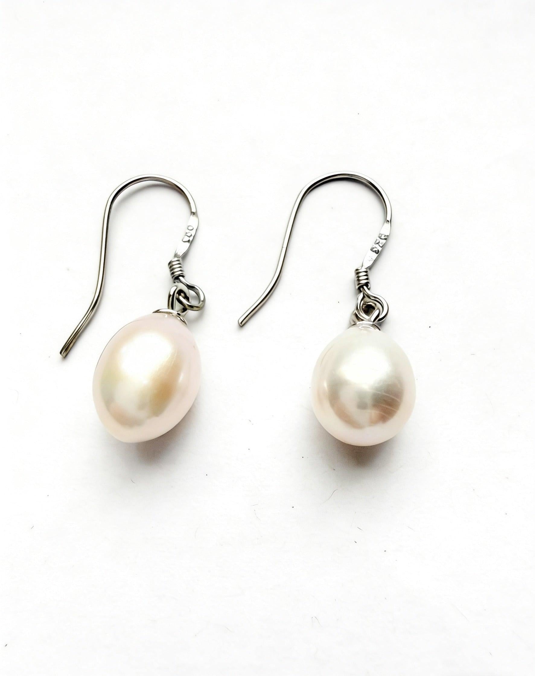 Baroque freshwater pearl drop earrings with 7-8mm white pearls on 925 sterling silver hooks against a white background.