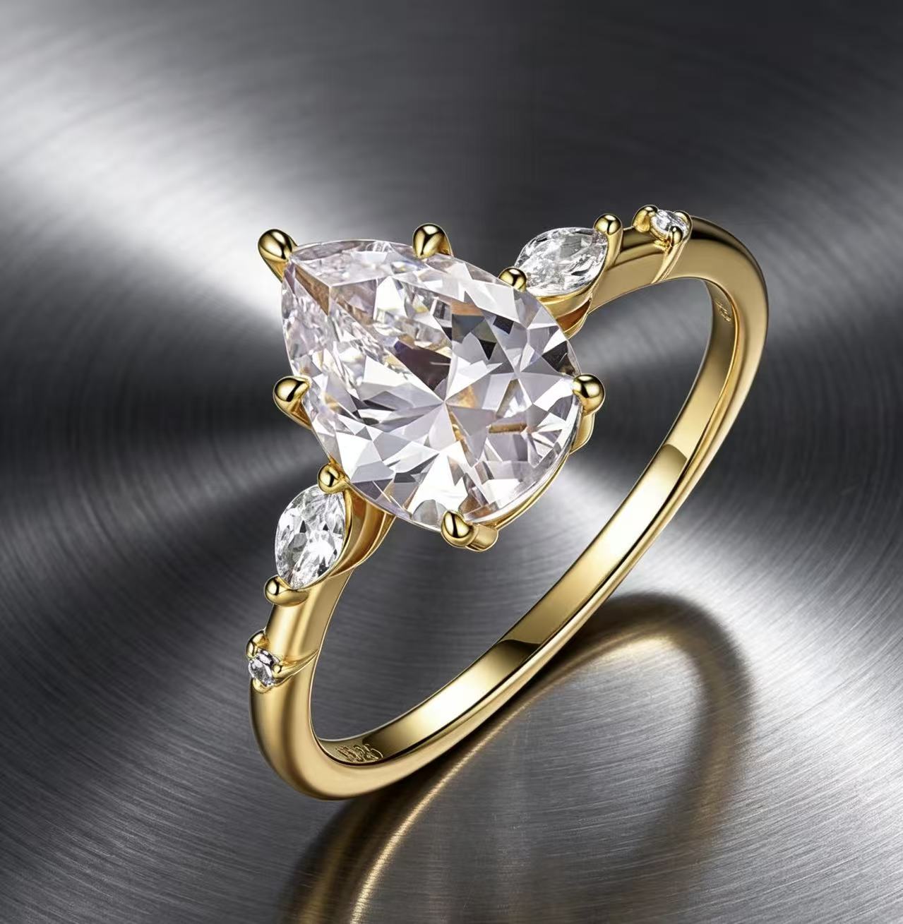 Gold pear-cut moissanite engagement ring with scattered marquise and round accent stones on a polished metallic background.