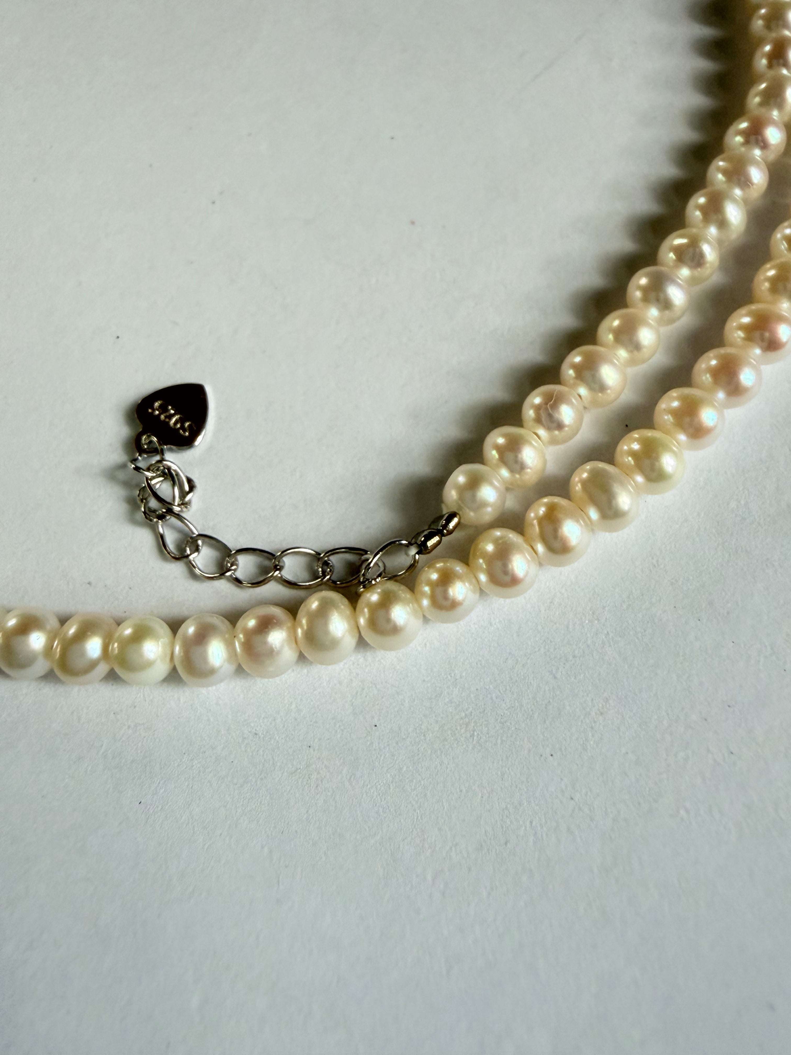 Minimalist 3–4mm freshwater pearl choker with a 925 sterling silver chain and heart-shaped charm on a white background.