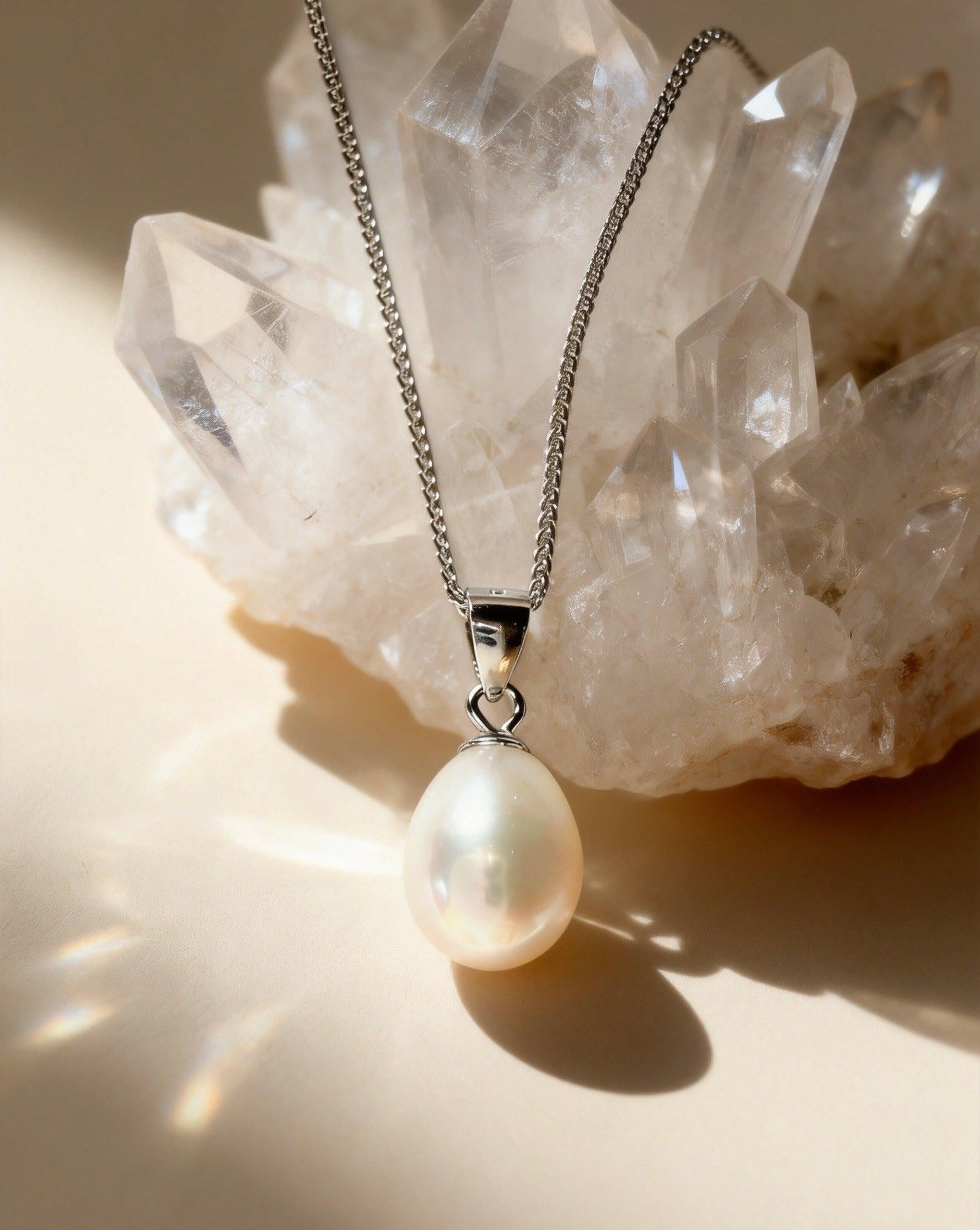 Baroque freshwater pearl pendant on a 925 sterling silver chain resting against a clear quartz crystal cluster.