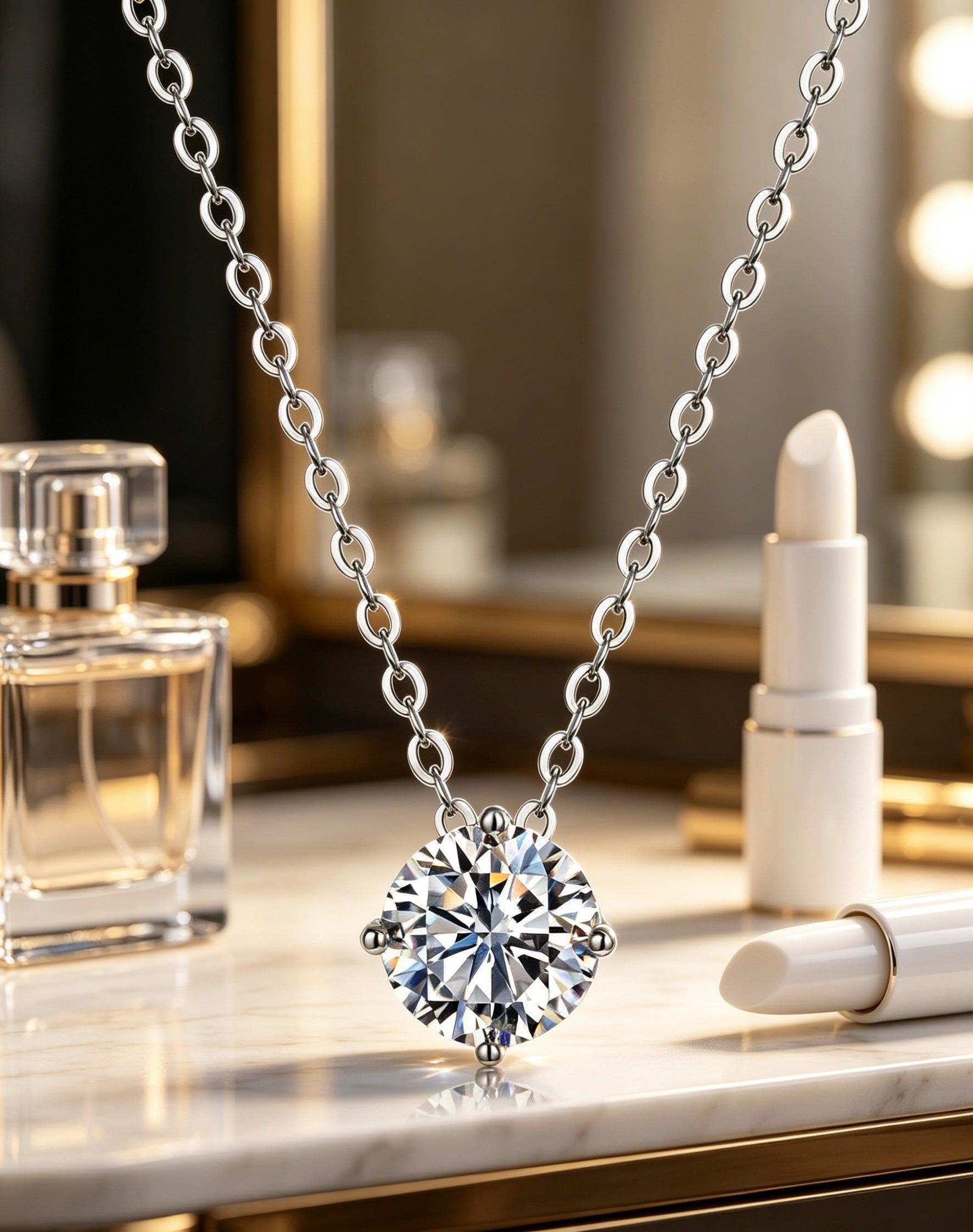Round brilliant-cut moissanite pendant on a sterling silver chain, featuring a classic four-prong crown setting.