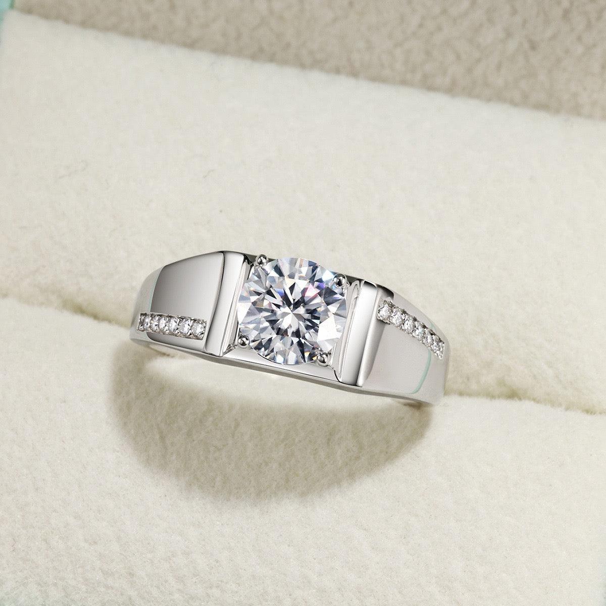 Men's 1ct round moissanite wedding ring in S925 silver with a pavé accent band in a white jewelry box.