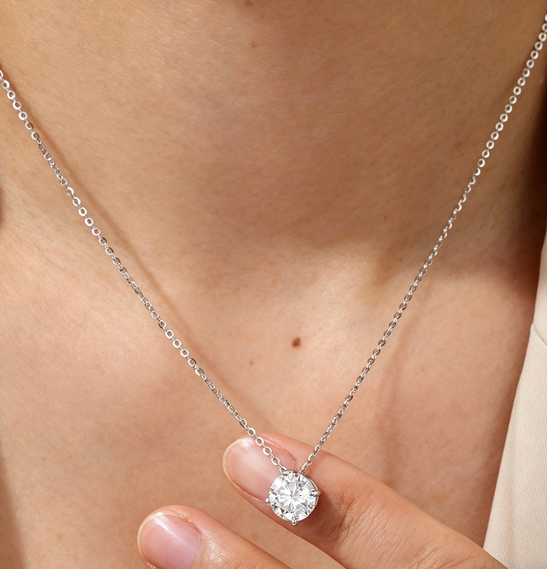 D-color VVS1 moissanite solitaire pendant necklace in a four-prong sterling silver setting worn on a delicate chain.