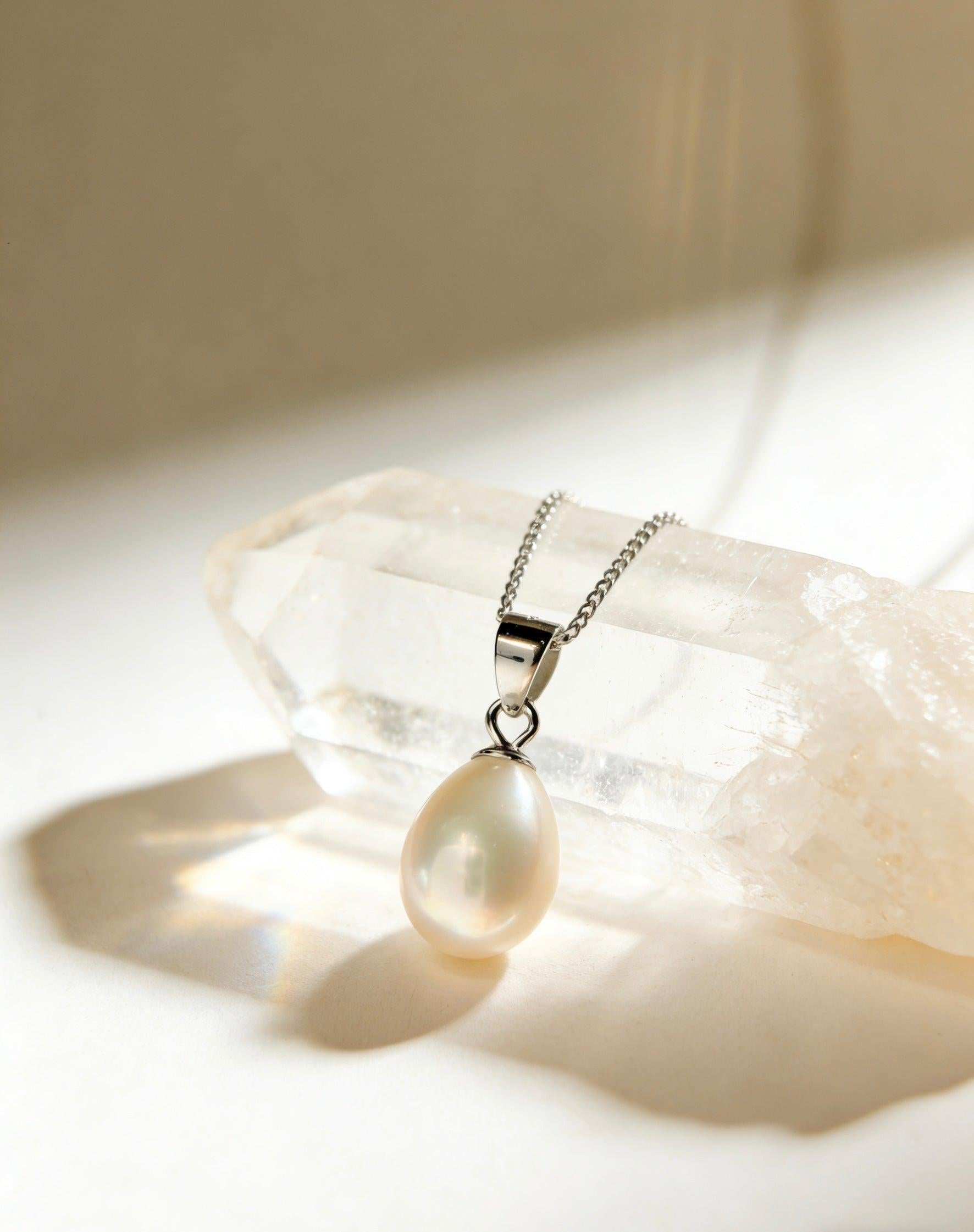 Baroque freshwater pearl pendant on a 925 sterling silver chain resting on a clear quartz crystal.