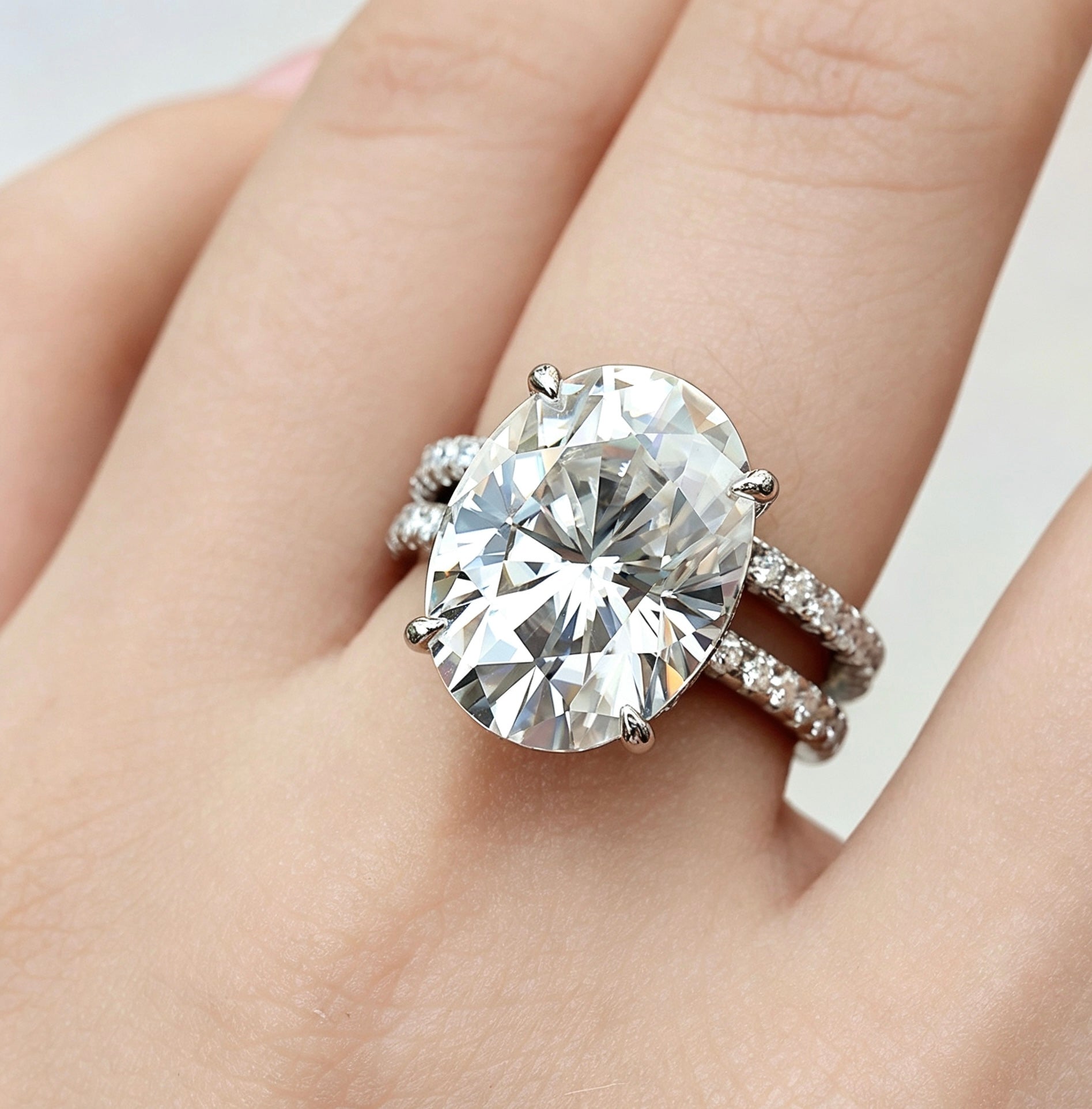 Large 12x16mm oval moissanite bridal set in S925 silver with pavé diamond bands worn on a finger.