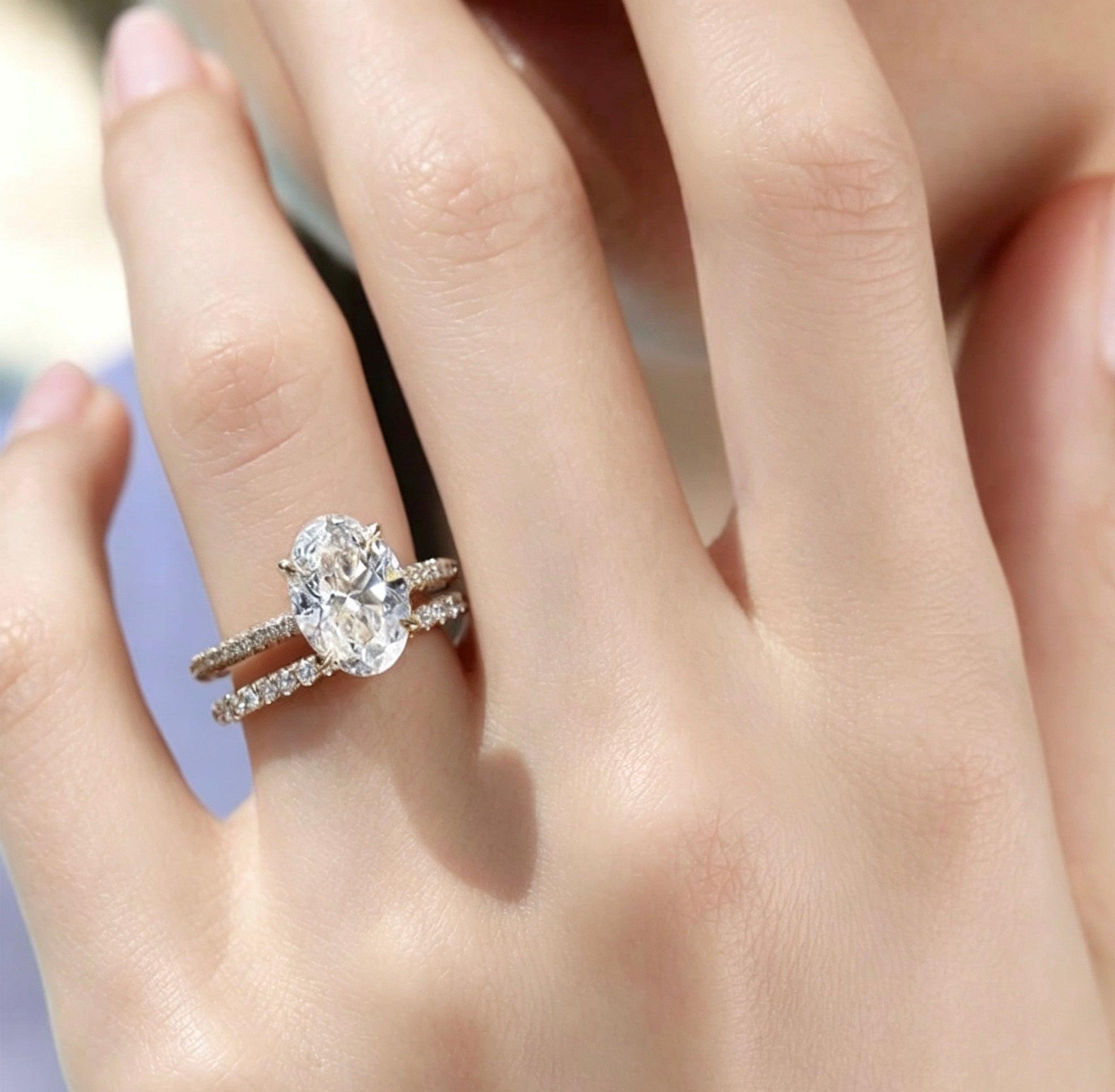 Oval moissanite solitaire engagement ring with a matching pavé band in S925 silver on a finger.