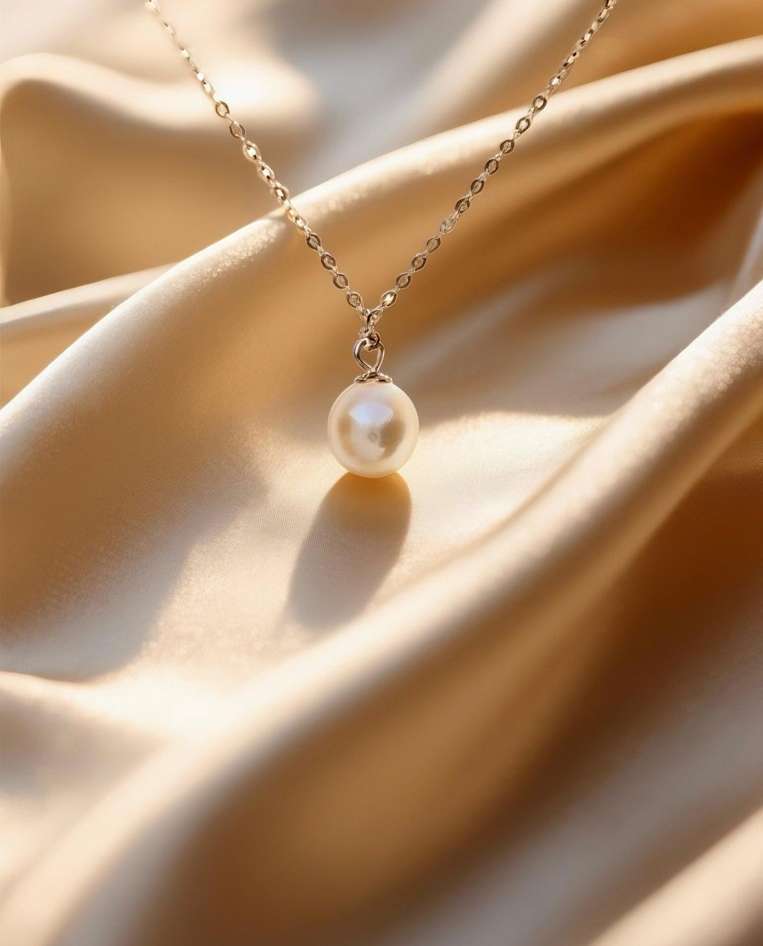 7mm lustrous Hepu saltwater pearl pendant on a delicate silver chain resting on soft gold satin fabric.
