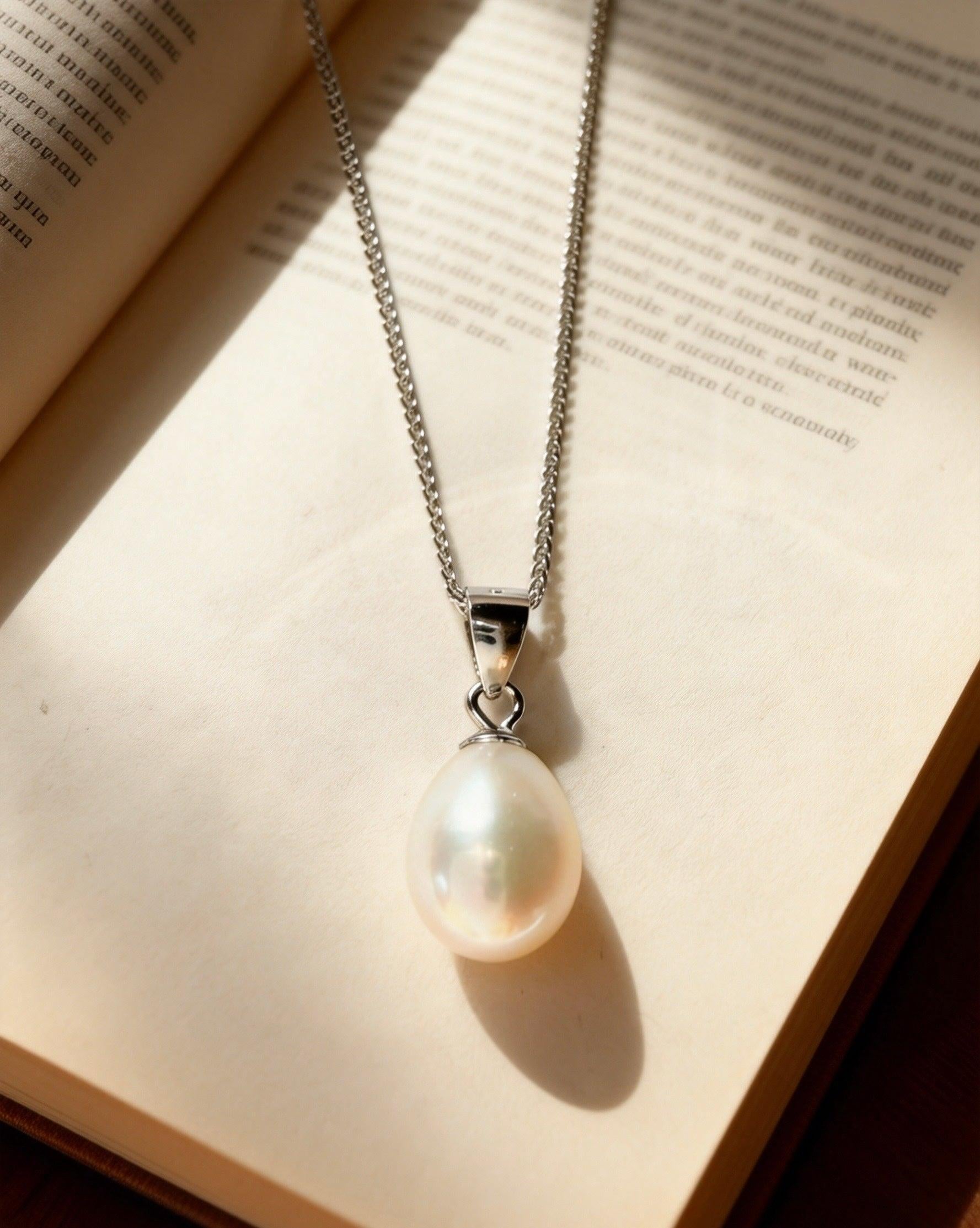 Baroque freshwater pearl pendant on a delicate 925 sterling silver chain resting on an open vintage book.