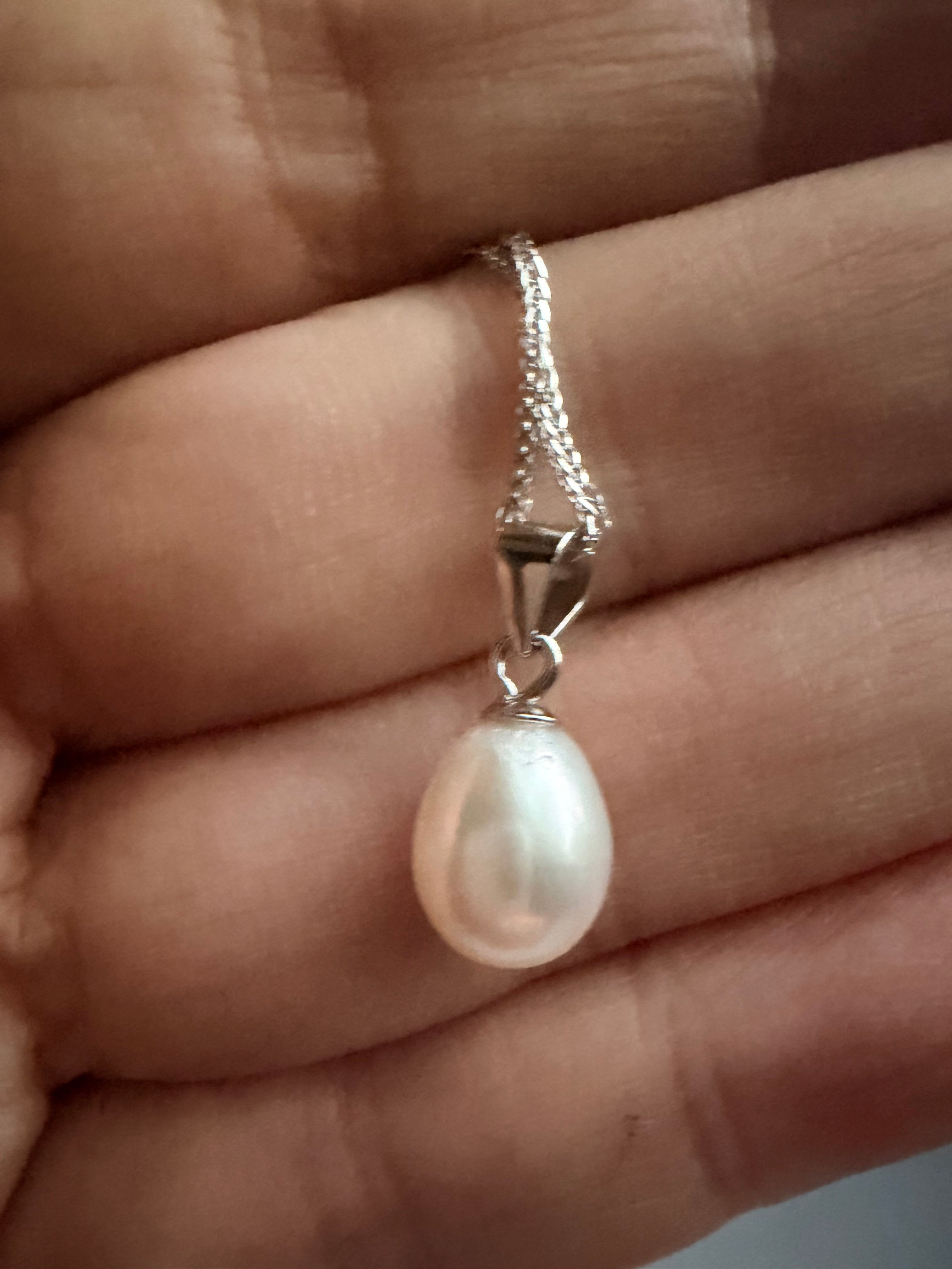 Baroque freshwater pearl pendant on a delicate 925 sterling silver chain held in a palm.